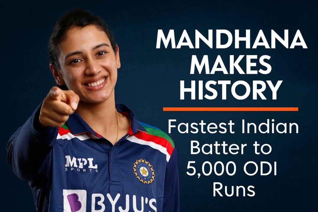 Smriti Mandhana smiling and pointing towards the camera in India’s blue cricket jersey, celebrating her milestone as the fastest Indian batter to reach 5,000 ODI runs.